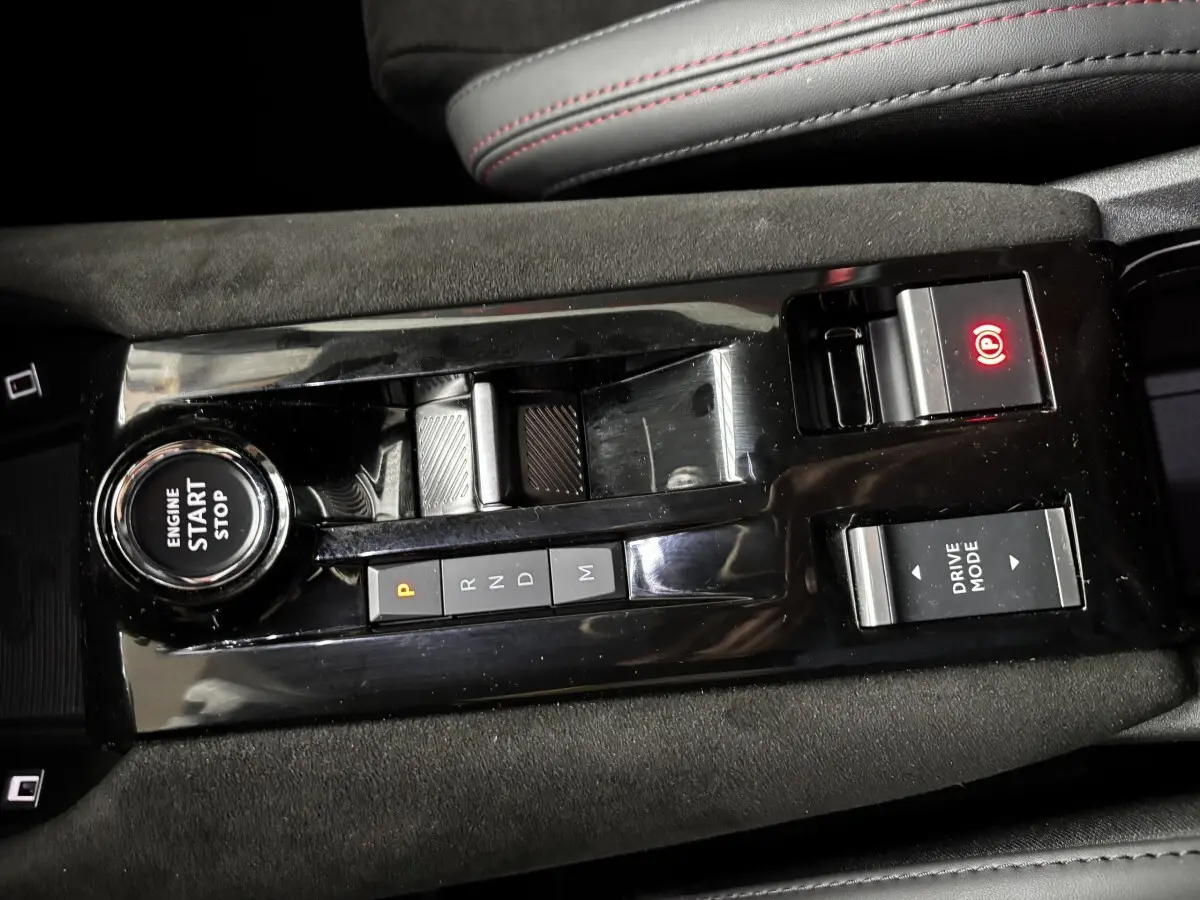 Vue rapprochée de la console centrale noire brillante de l'Alfa Romeo Junior 2024 avec boutons de démarrage, boîte auto et mode de conduite.