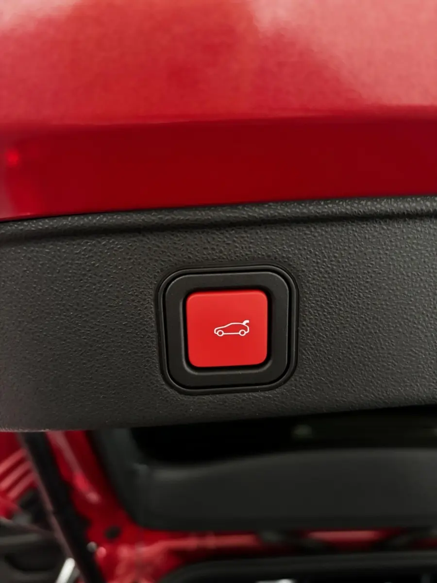Gros plan sur le bouton rouge d'ouverture électrique du coffre d'une Alfa Romeo Junior rouge 2024.