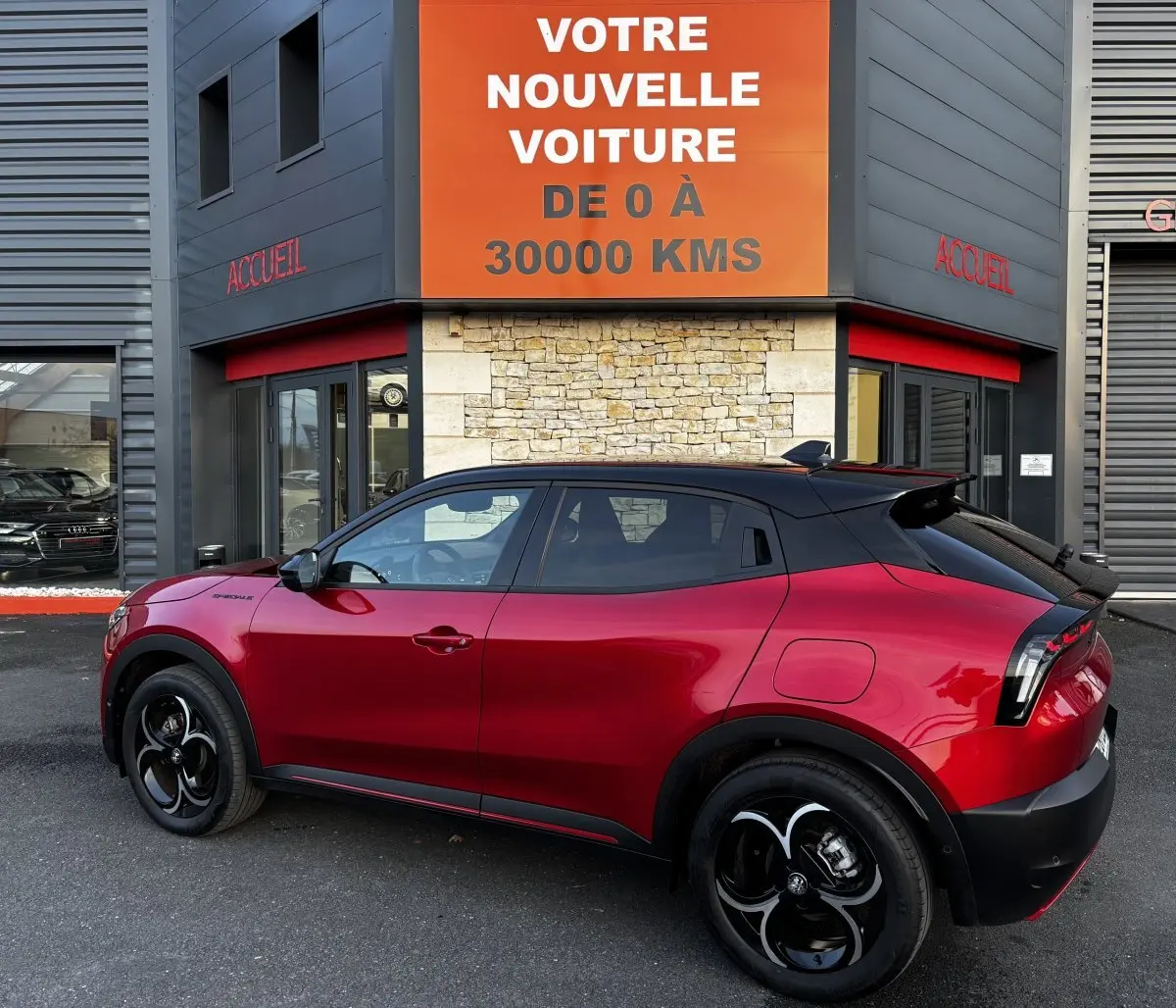 Vue latérale droite d'un Alfa Romeo Junior 1.2 Ibrida rouge avec toit noir et jantes noires au design distinctif.