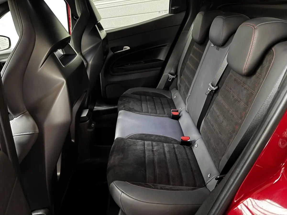 Vue intérieure côté droit des sièges arrière en cuir et alcantara noirs avec surpiqûres rouges d'une Alfa Romeo Junior rouge 2024.