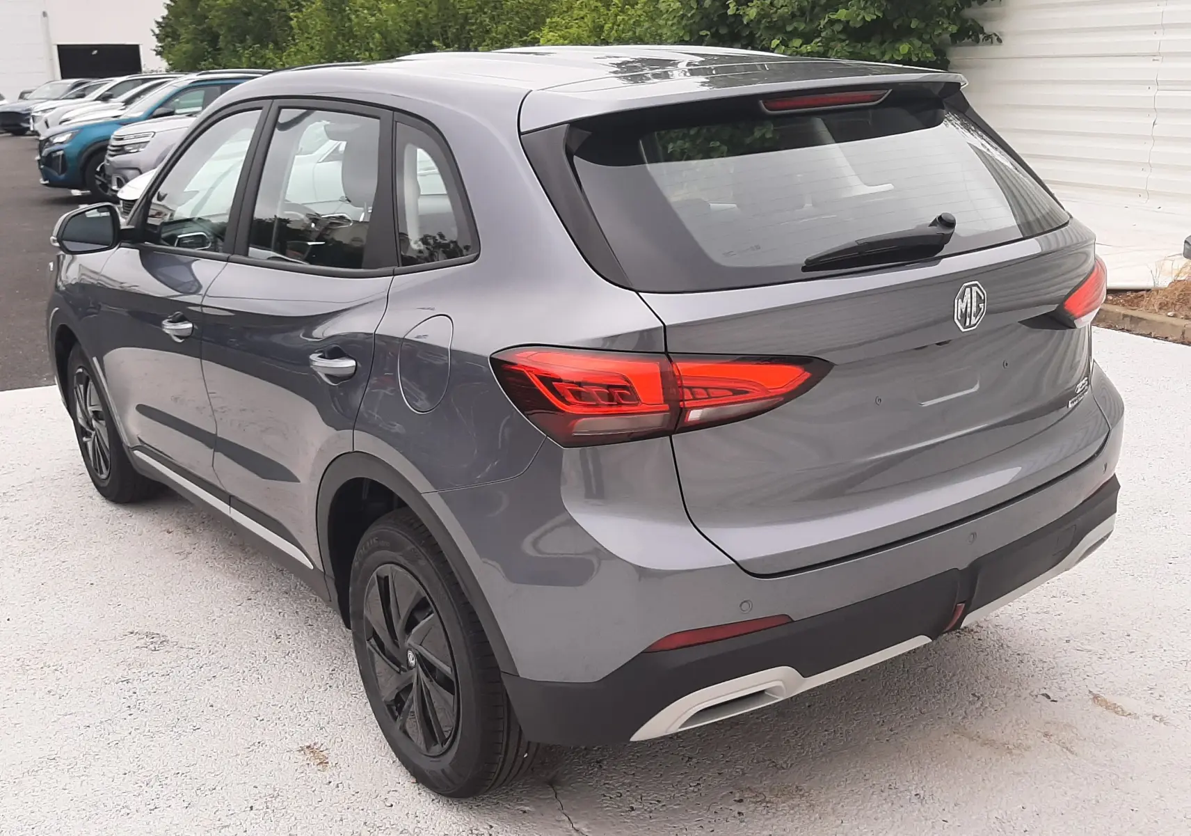 Vue 3/4 arrière droite du MG ZS 1.5 HYBRID+ 197CH 2026 en gris Camden avec feux arrière LED et jantes noires.
