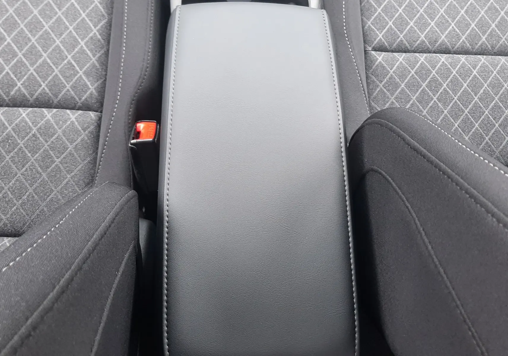 Vue plongeante sur l'accoudoir central noir et les sièges gris à motifs en losange de la MG MOTOR ZS Camden Grey 2026.