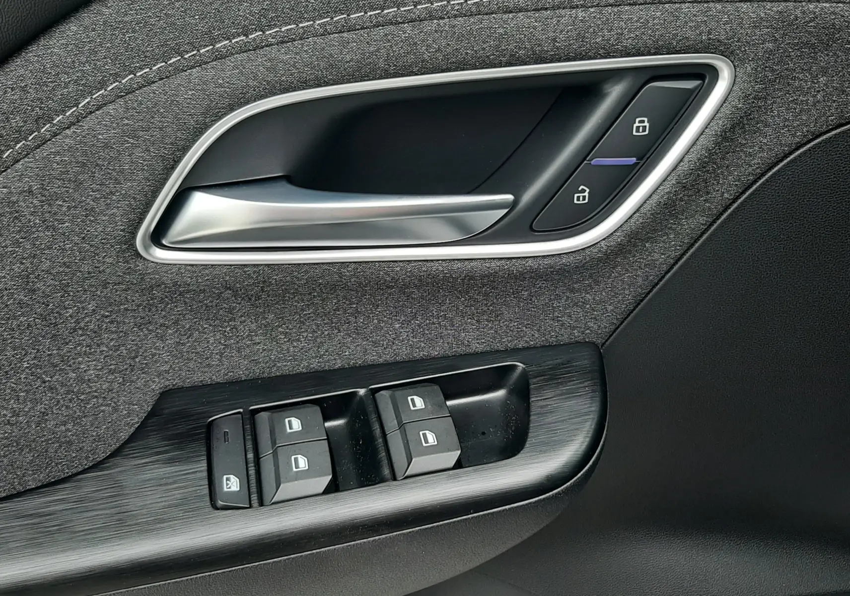 Gros plan sur la poignée intérieure et les commandes de porte côté conducteur du MG ZS 1.5 HYBRID+ 2026 en Camden Grey.