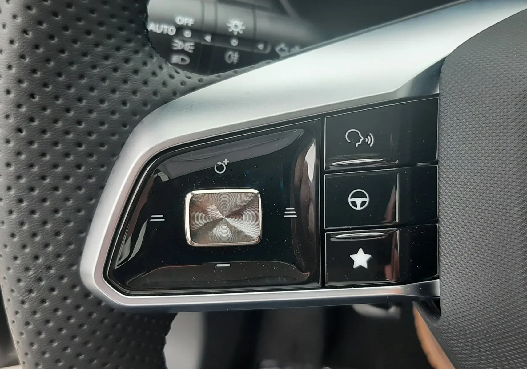 Gros plan sur les commandes gauche du volant perforé du MG Motor ZS Camden Grey 2026 hybride avec boutons multifonctions.