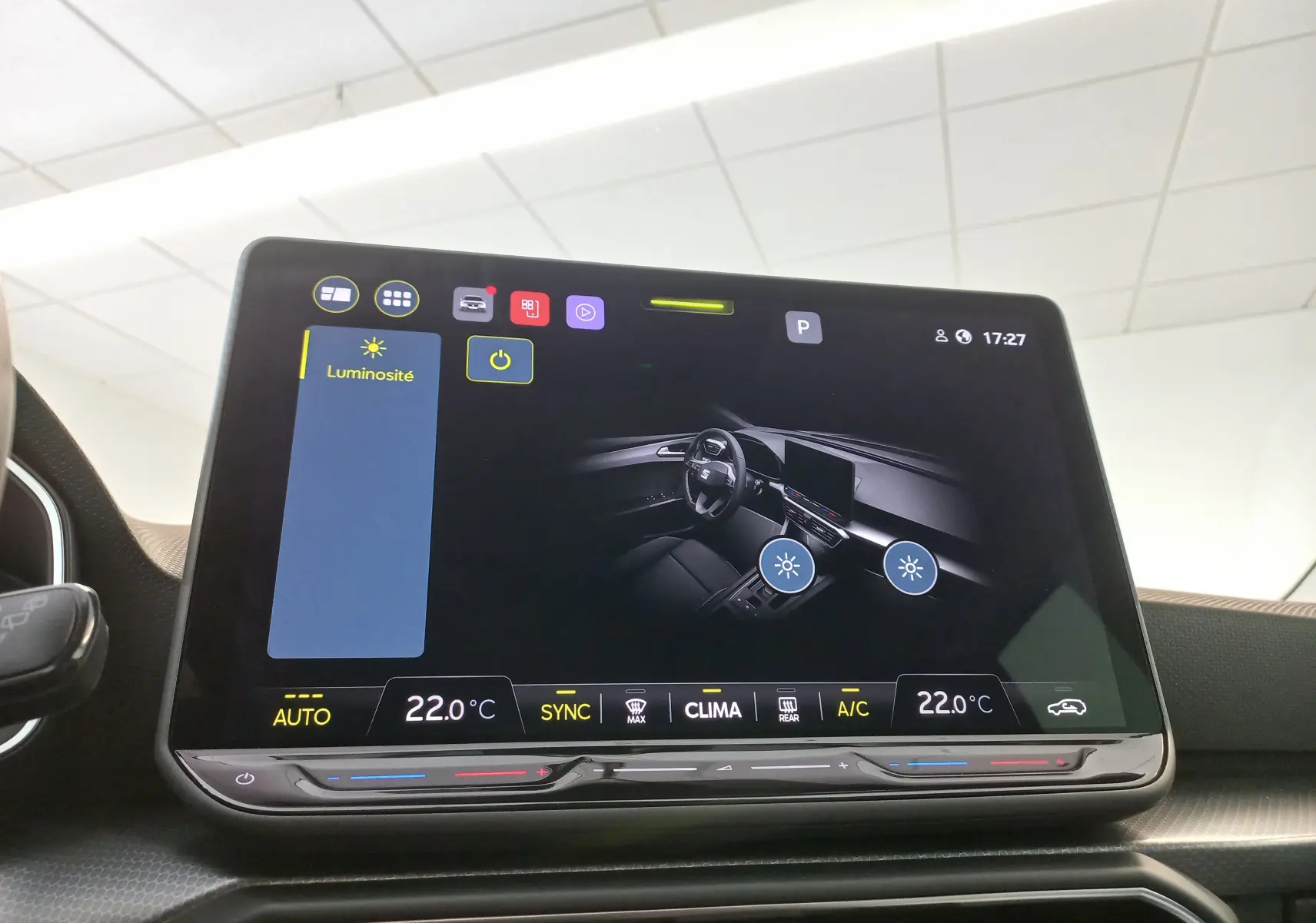Écran tactile central affichant les réglages de luminosité et climatisation dans une SEAT LEON Bleu Saphir 2025.