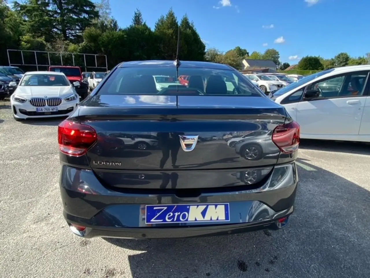 Vue arrière d'une Dacia Logan gris foncé 2022 avec feux rouges et plaque d'immatriculation Zéro KM visible.