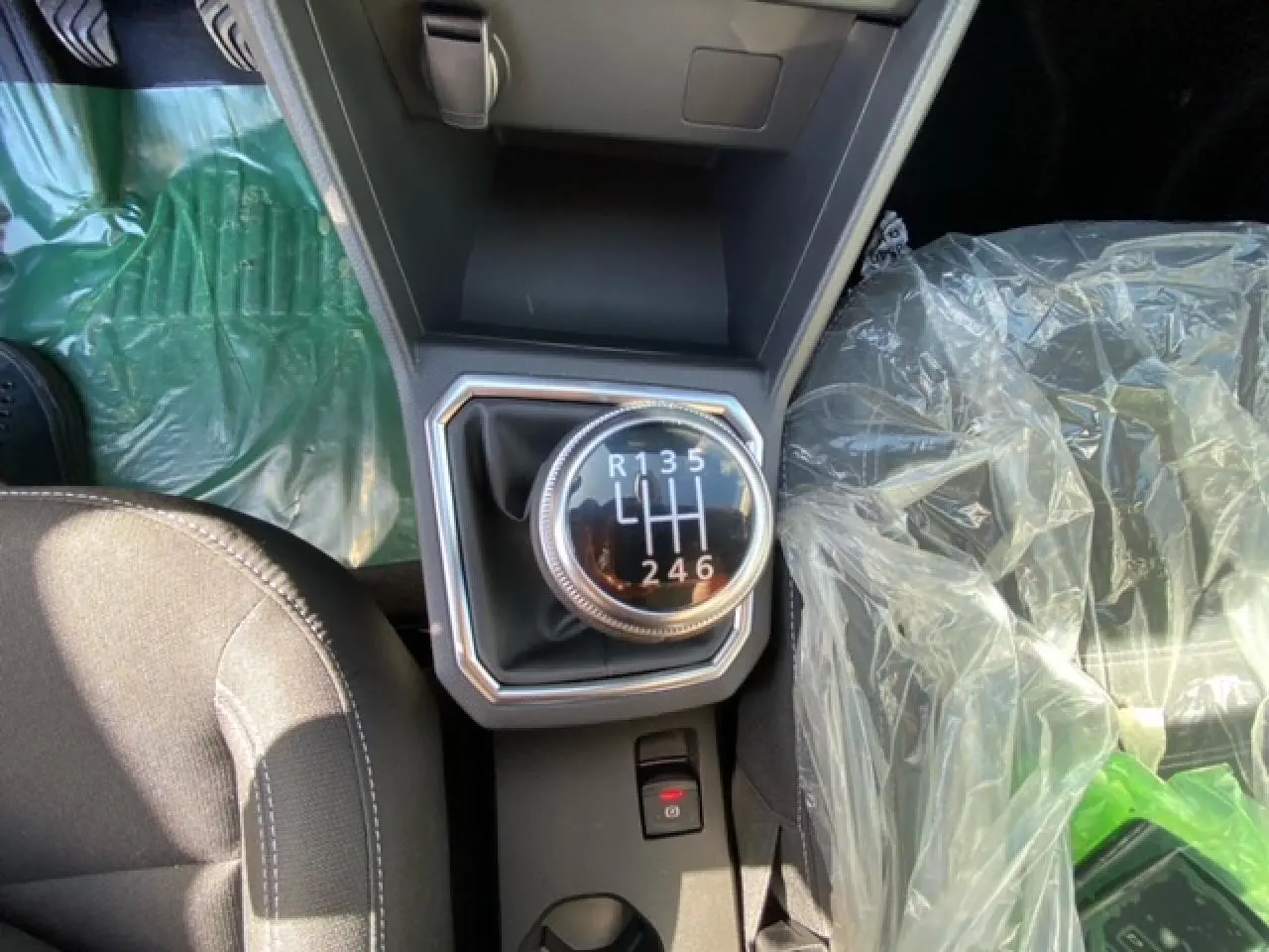 Gros plan sur le levier de vitesse manuel de la Dacia Logan gris 2022, avec siège passager protégé par un film plastique.