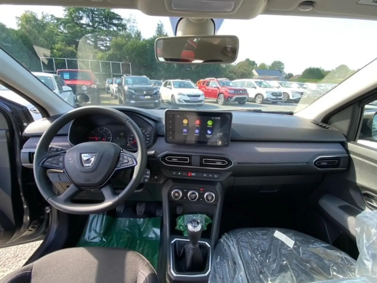 Vue intérieure avant de la Dacia Logan 2022 essence grise, avec volant multifonction, écran tactile Media Nav et boîte manuelle.