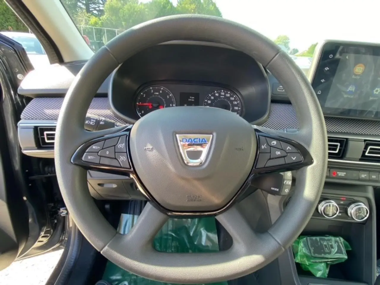 Vue rapprochée du volant gris de la Dacia Logan 2022 avec commandes intégrées et écran tactile Media Nav visible.