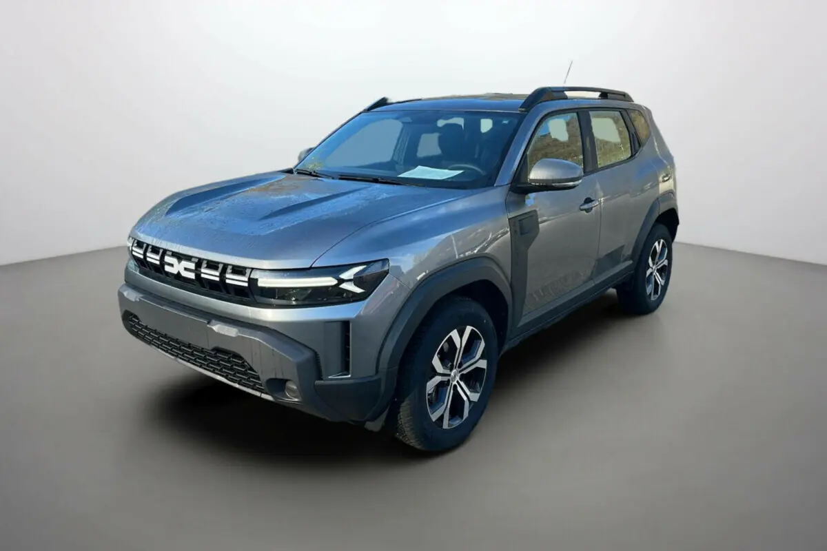 SUV Dacia Duster 2025 gris schiste en 3/4 avant droit avec calandre distinctive et barres de toit noires.