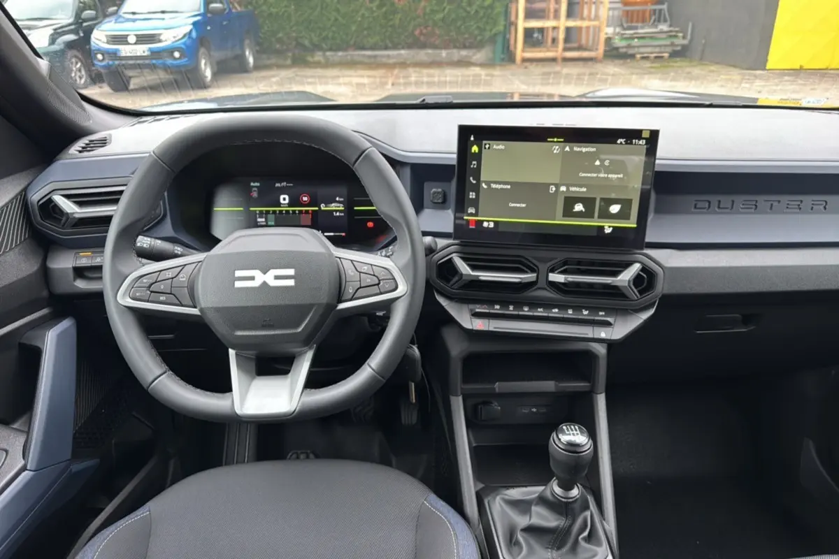 Intérieur du Dacia Duster 2025 gris schiste, vue de face sur le volant, tableau de bord numérique et écran tactile central.
