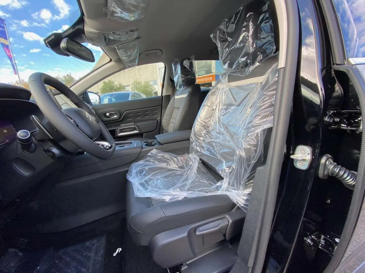 Intérieur côté conducteur du Citroën C5 Aircross noir perla 2025, sièges avant protégés par film plastique.