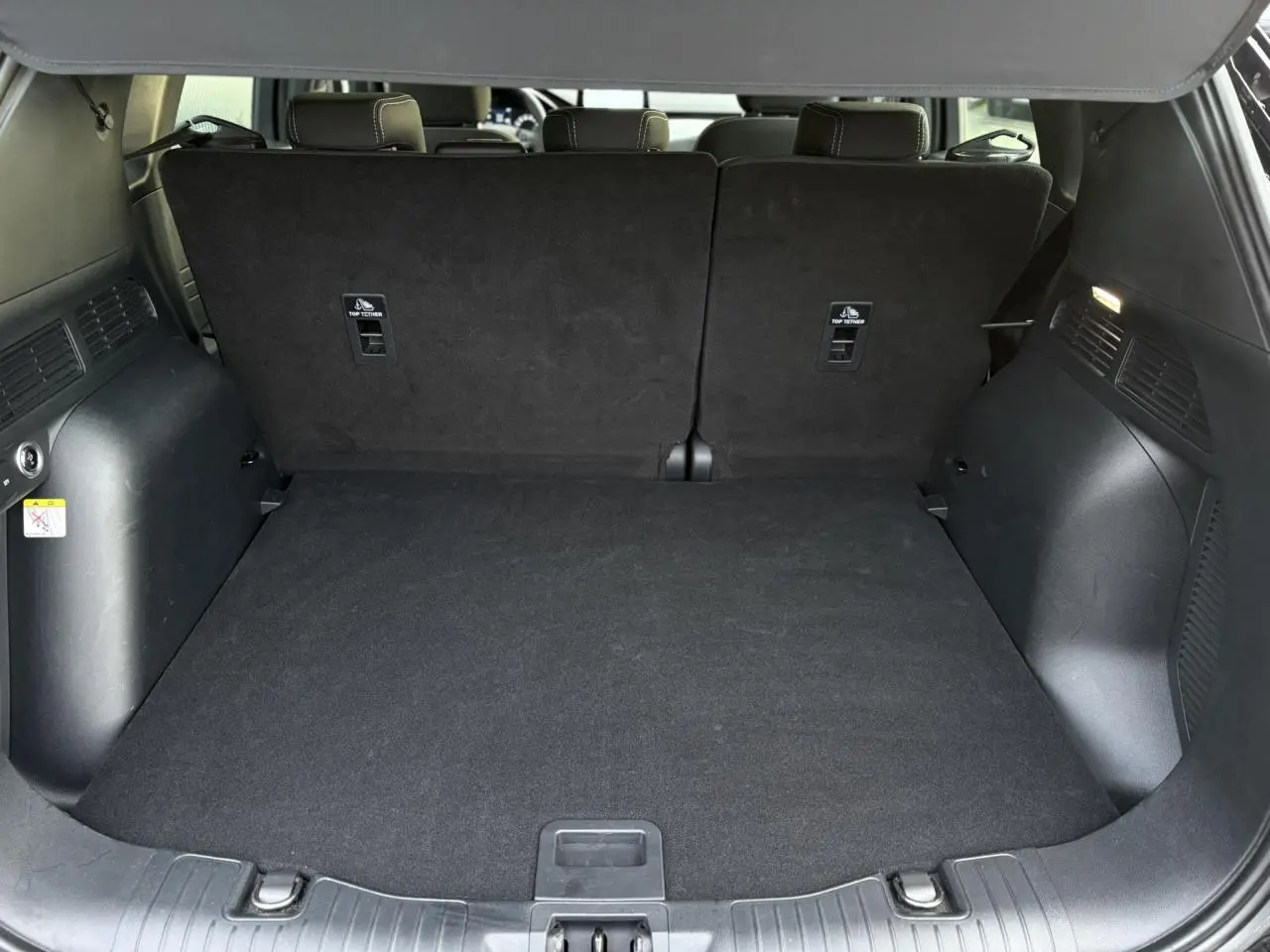 Coffre spacieux du Ford Kuga 2024 noir Obsidien, vue depuis l'arrière avec banquette arrière relevée et plancher plat.