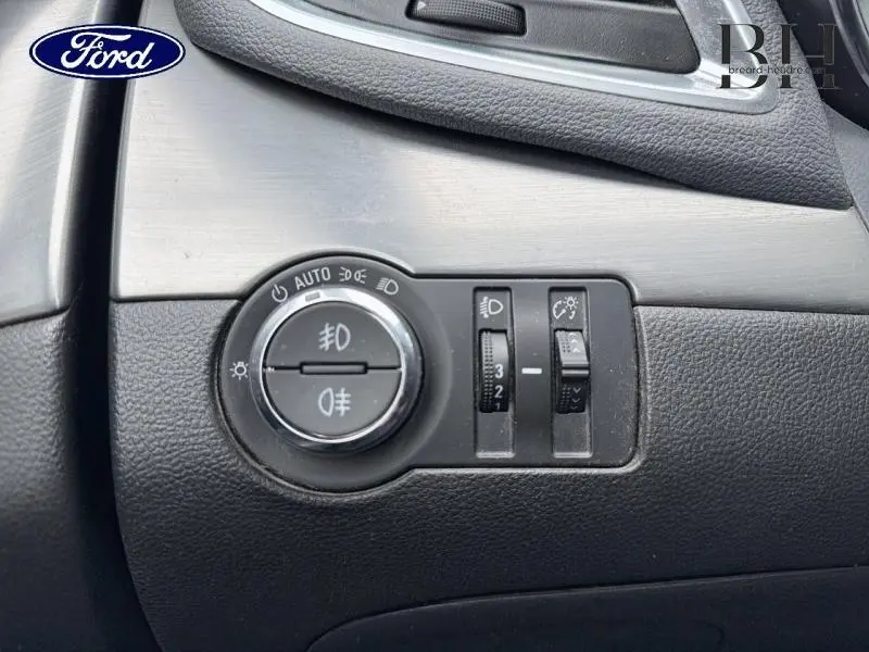 Panneau de commandes d'éclairage intérieur noir sur tableau de bord, avec molette et réglages lumineux.