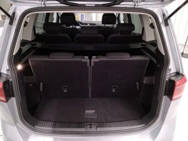 Vue arrière ouverte du coffre gris du Volkswagen Touran 2025, montrant les sièges rabattus et l'espace de chargement.