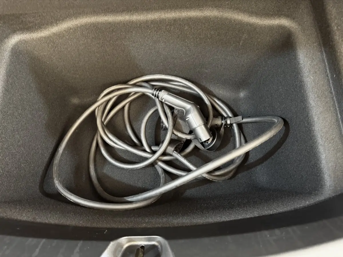 Câble de recharge électrique noir dans le coffre avant d'une Tesla Model 3 Grande Autonomie 2023.