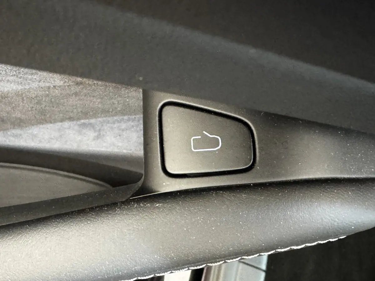 Bouton de déverrouillage de coffre noir sur la portière intérieure d'une Tesla Model 3 Grande Autonomie 2023.