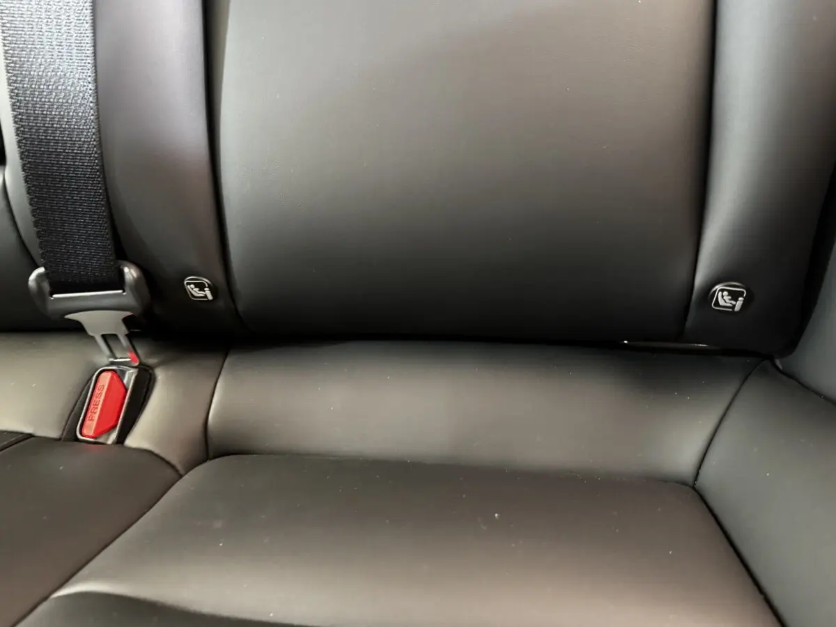 Gros plan sur la banquette arrière noire de la Tesla Model 3 2023 avec ceintures et fixations ISOFIX visibles.