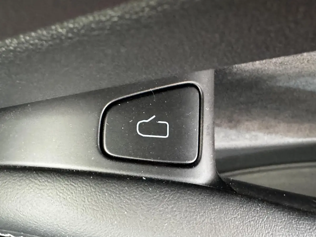 Gros plan sur le bouton de déverrouillage intérieur noir de la Tesla Model 3 Grande Autonomie 2023.