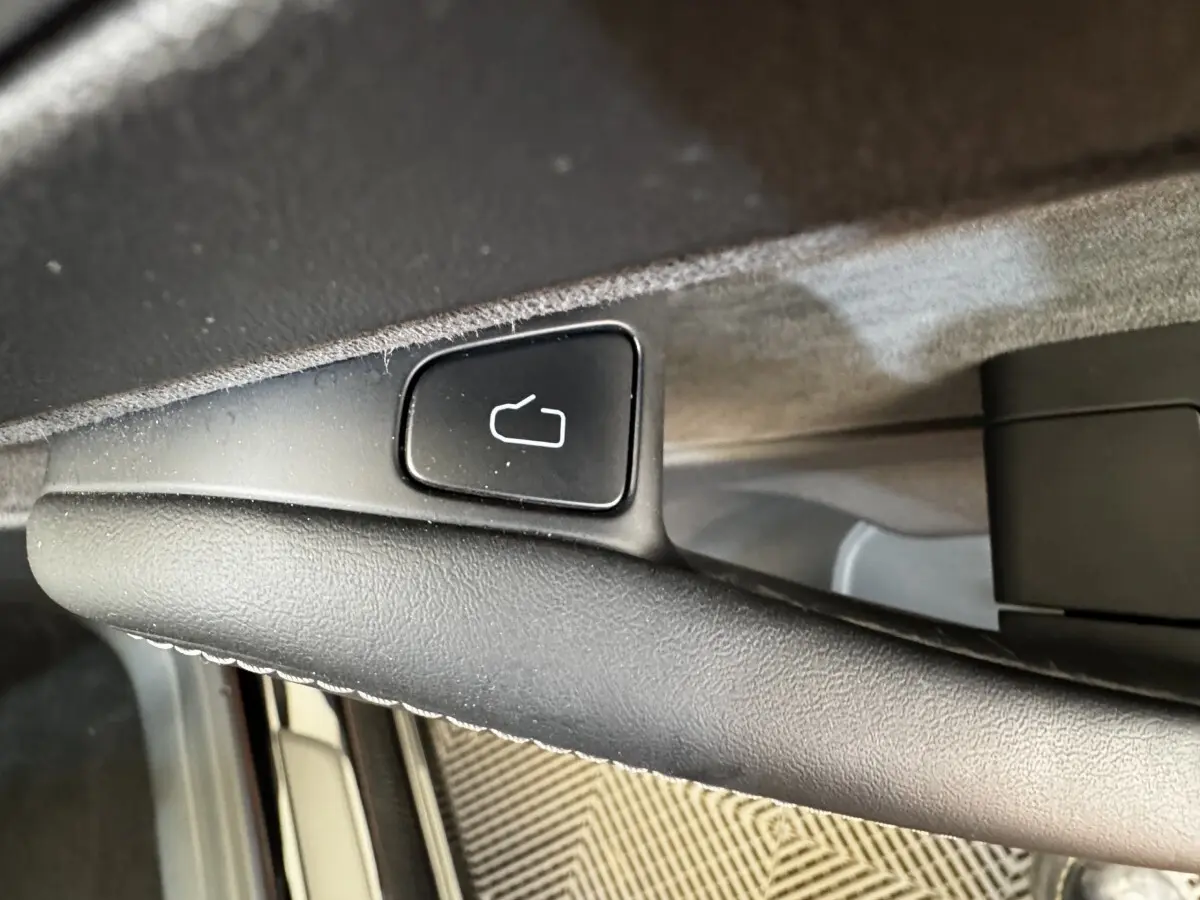 Détail du bouton de déverrouillage de porte sur la poignée intérieure noire d’une Tesla Model 3 Grande Autonomie 2023.