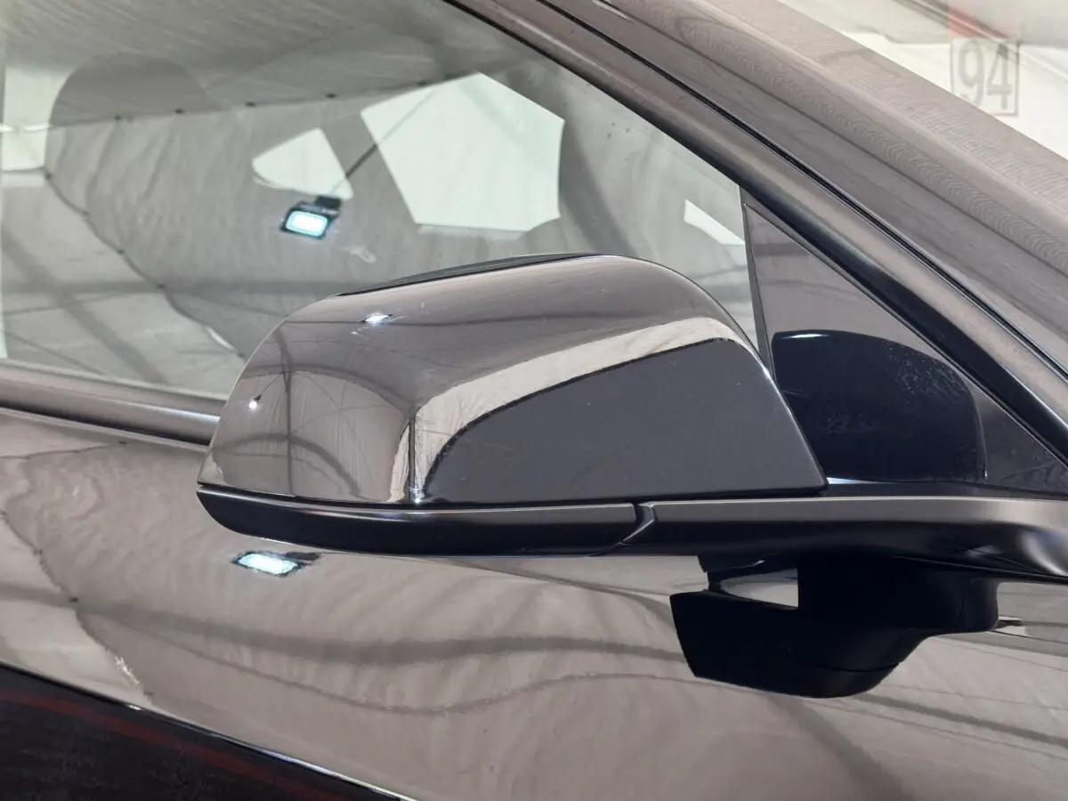 Rétroviseur extérieur noir côté conducteur d'une Tesla Model 3 Grande Autonomie 2023, vue rapprochée.