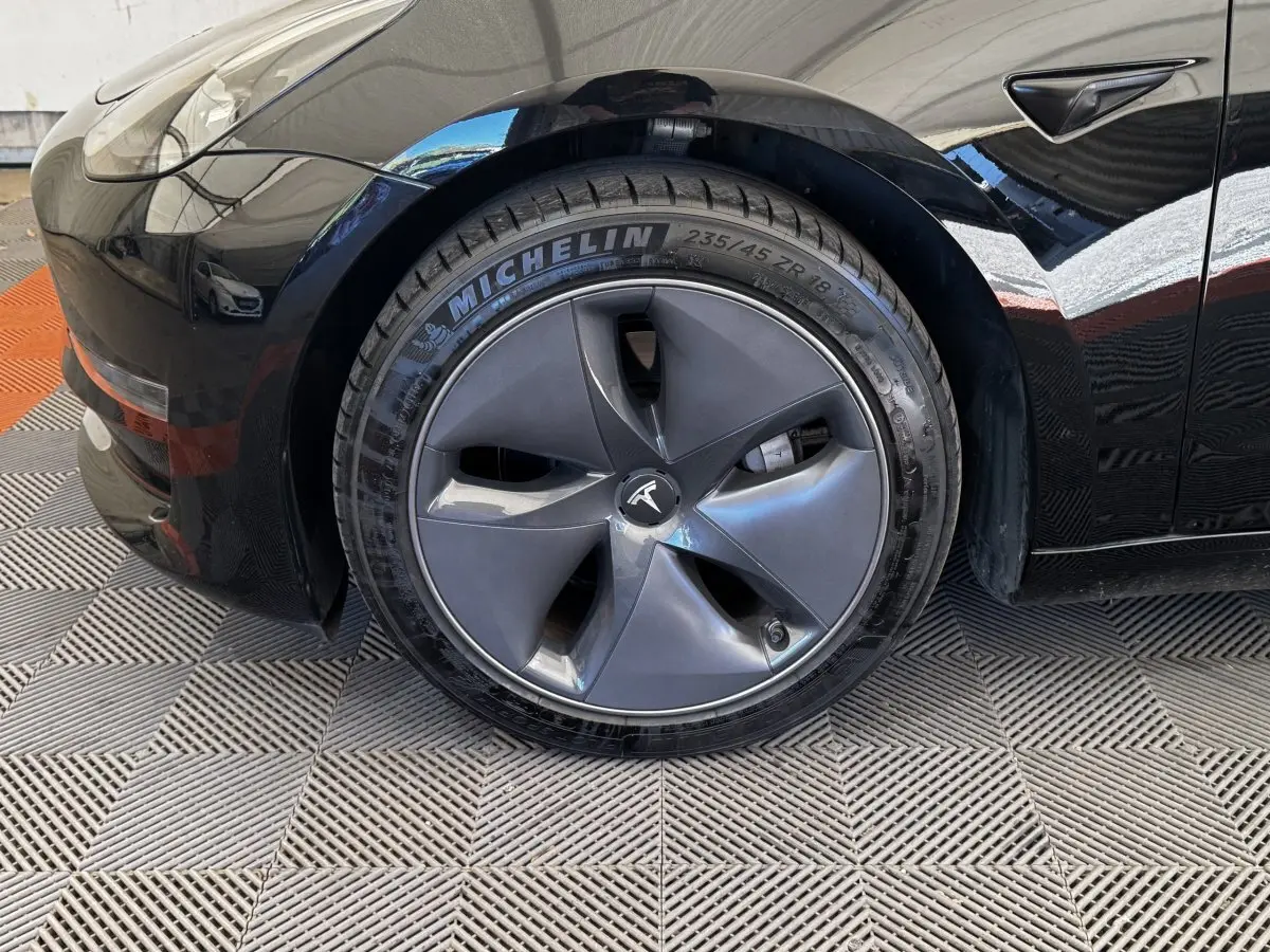Gros plan sur la roue avant gauche noire d'une Tesla Model 3 2023 avec jante aérodynamique et pneu Michelin.