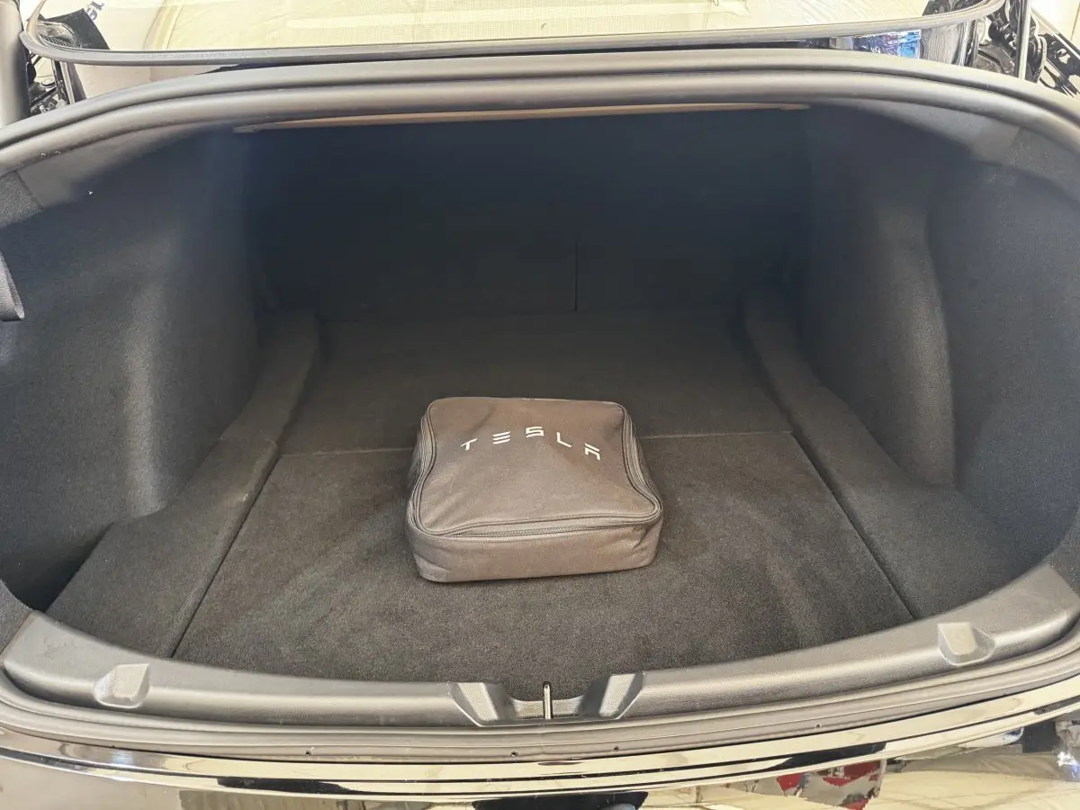 Coffre ouvert d'une Tesla Model 3 noire 2023, avec sac de charge Tesla au centre, vue arrière.