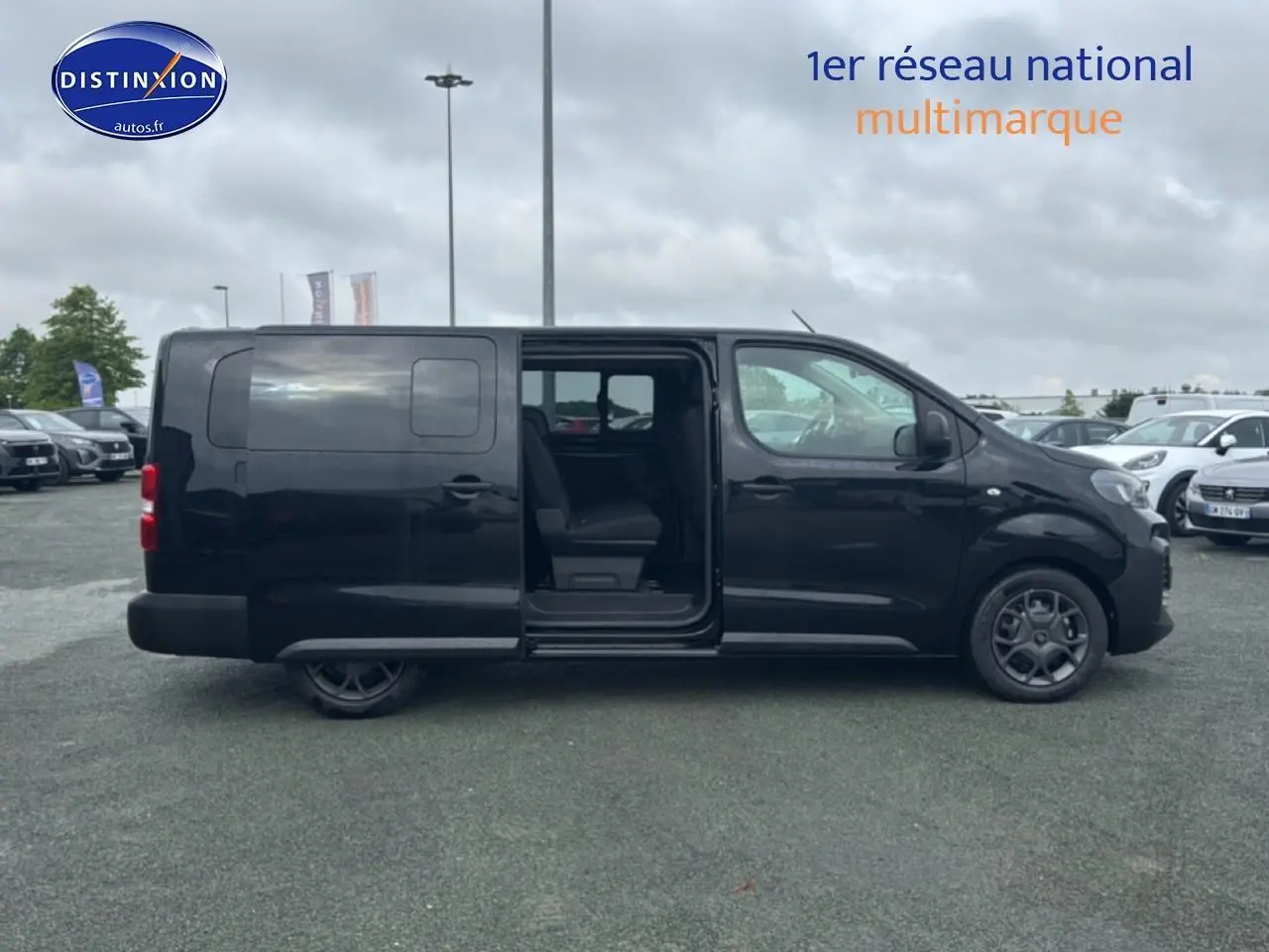 Profil droit d'un FIAT Scudo Combi noir 2026 avec porte latérale coulissante ouverte sur parking.
