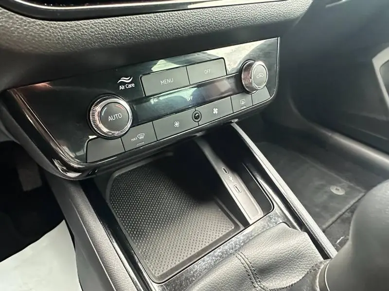Détail de la console centrale noire du Skoda Scala blanc, montrant les commandes de climatisation automatique et un espace de rangement.