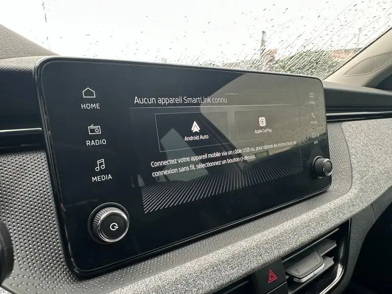 Gros plan sur l'écran tactile central noir du tableau de bord gris clair d'une Skoda Scala blanc cristal.