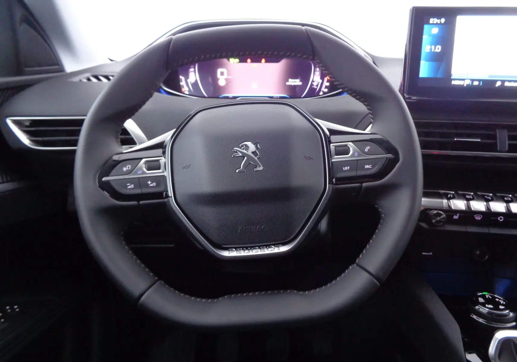 Vue rapprochée du volant cuir noir du Peugeot 3008 2023 avec tableau de bord numérique et commandes intégrées.