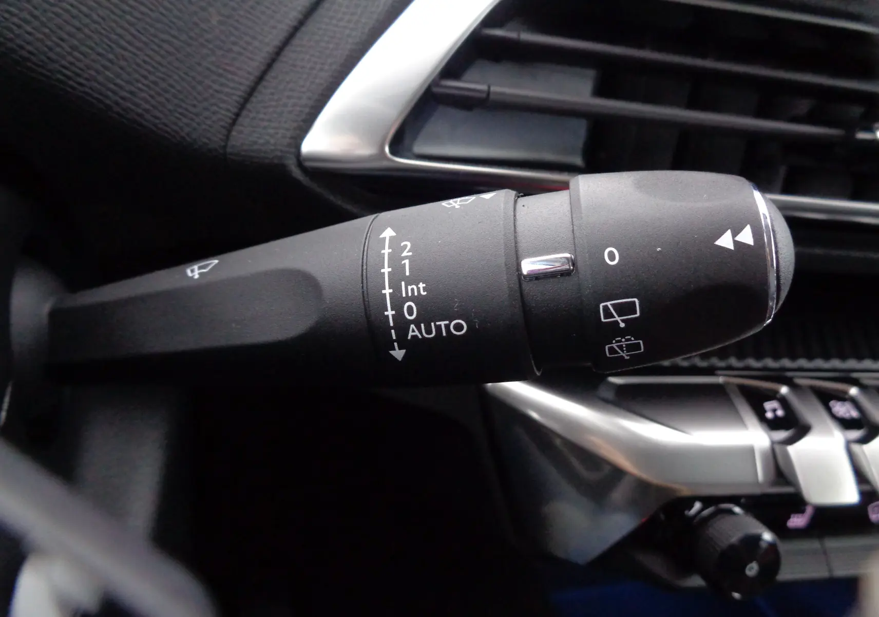 Gros plan sur la commande des essuie-glaces du Peugeot 3008 gris Artense 2023, avec détails des réglages et aérateurs chromés.