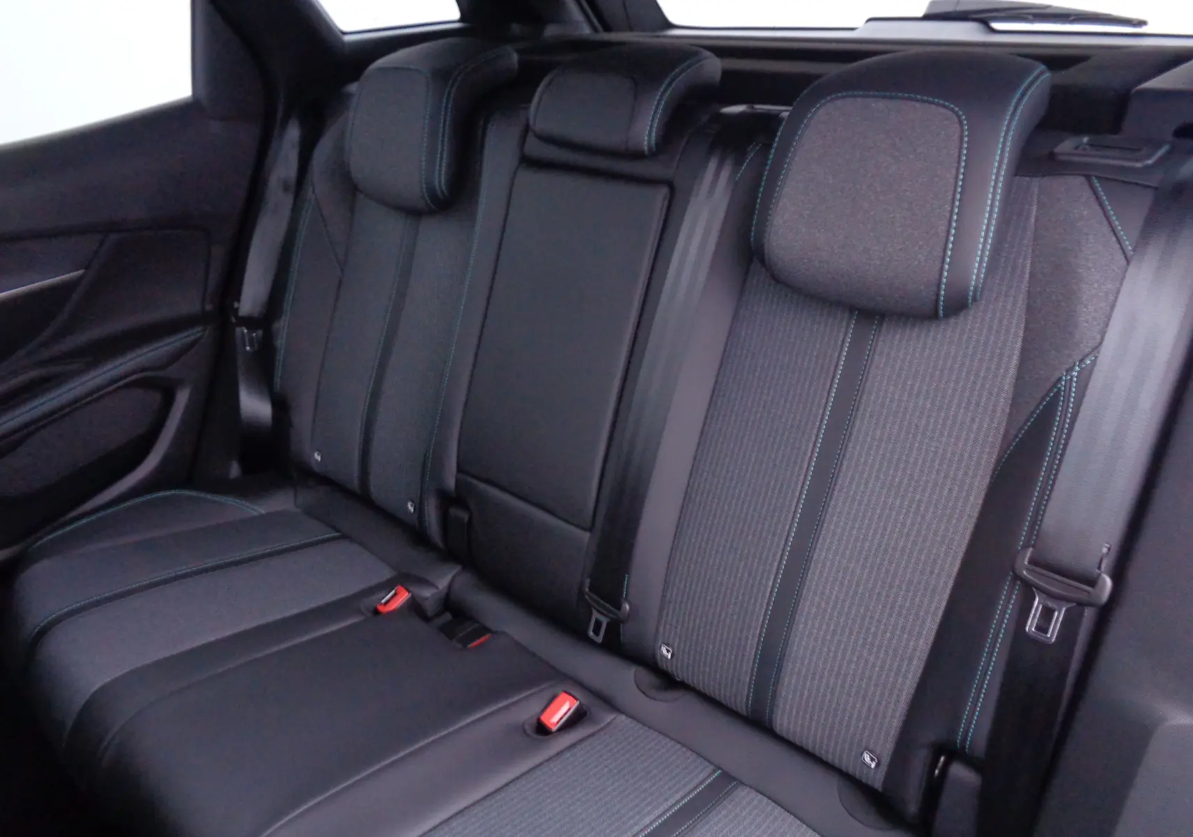 Vue intérieure arrière des sièges du Peugeot 3008 2023, revêtement tissu et cuir noir avec surpiqûres bleues.