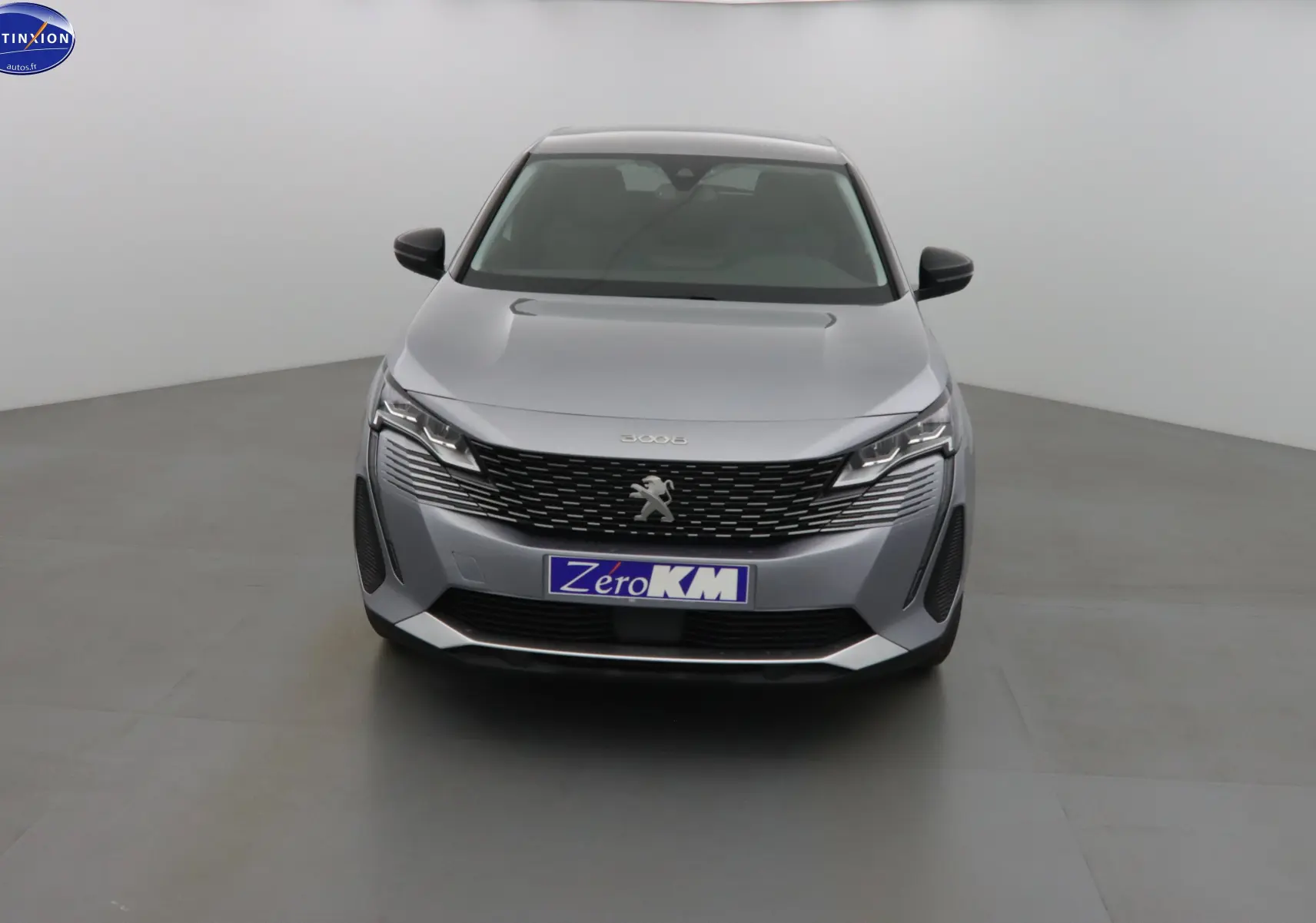 Vue frontale d'un Peugeot 3008 gris Artense métal avec calandre noire et plaque "Zero KM" visible.