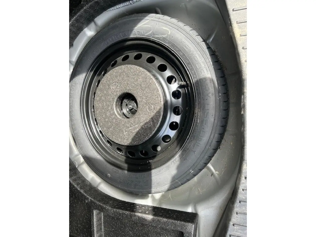 Gros plan sur la roue de secours galette noire dans le coffre d’un Ford C-MAX gris clair 2018.