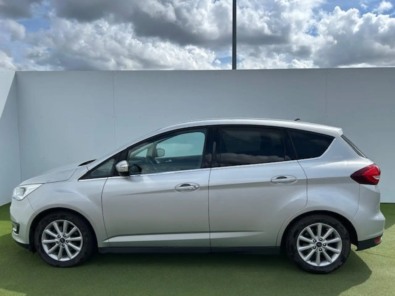 Ford C-MAX II gris clair métal vu de profil côté gauche, avec vitres arrière surteintées et jantes alliage 16 pouces.
