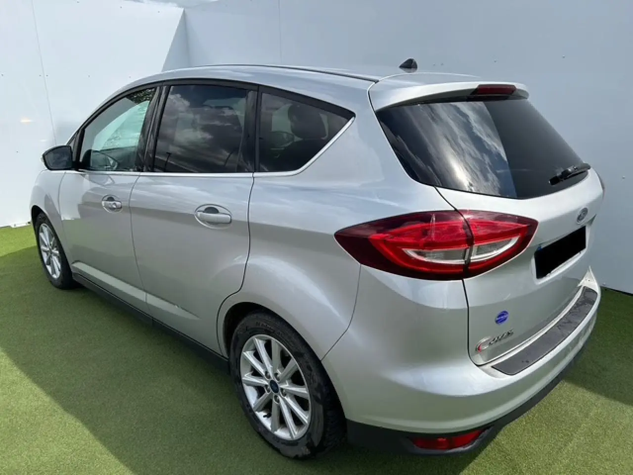 Vue 3/4 arrière droite d'une Ford C-MAX II gris clair métallisé avec vitres arrière surteintées et jantes alliage 16 pouces.