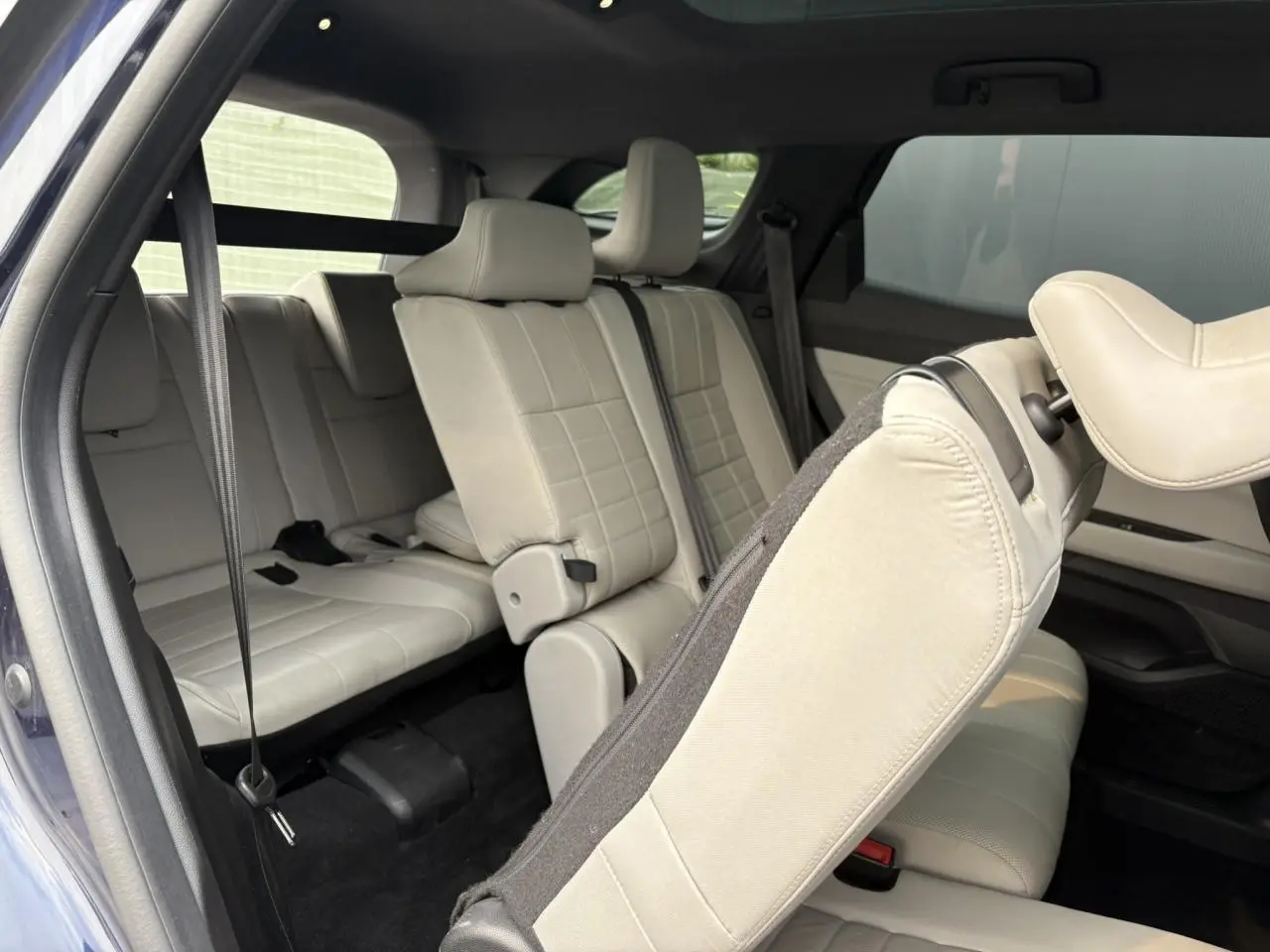 Vue intérieure arrière du Renault Espace VI 2023, sièges cuir gris sable clair avec toit panoramique visible.