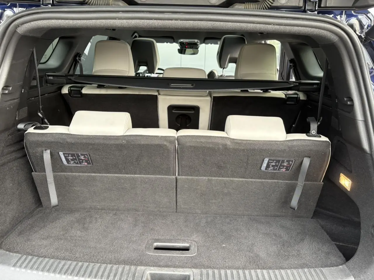 Coffre ouvert vue arrière du Renault Espace bleu nuit, montrant la troisième rangée de sièges gris sable clair.