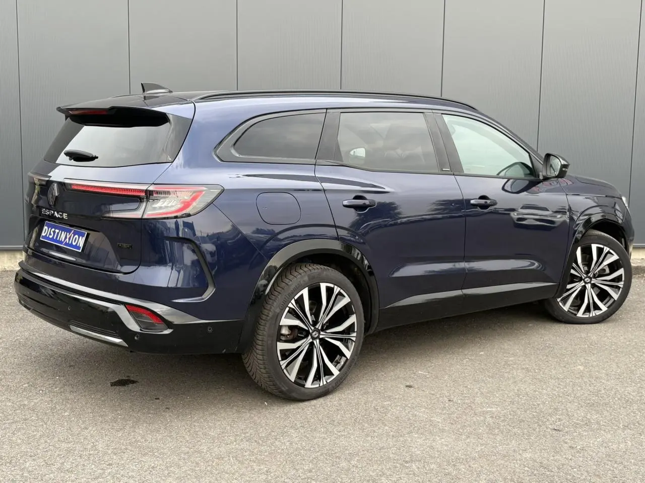 Vue 3/4 arrière droite d'un Renault Espace bleu nuit avec toit panoramique et jantes alliage noires diamantées.