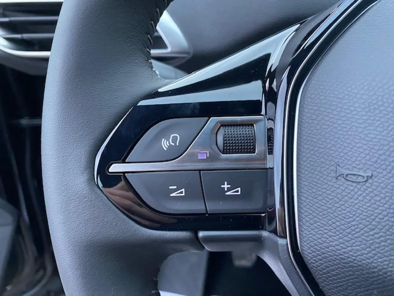 Gros plan sur les commandes vocales et volume au volant noir du Peugeot 5008 2023 essence finition Active Pack.