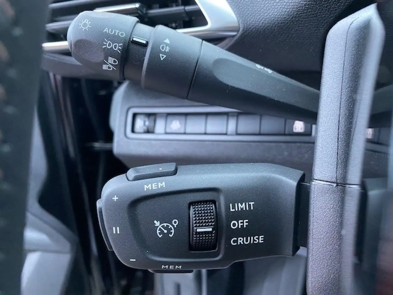 Gros plan sur les commandes de régulateur de vitesse et des feux sur la colonne de direction d'un Peugeot 5008 noir 2023.