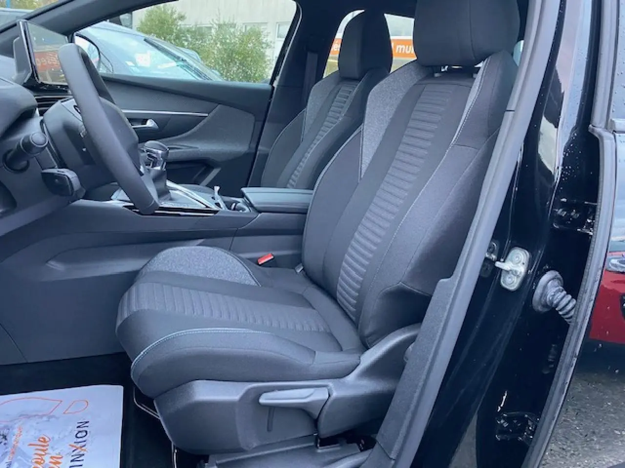 Vue intérieure côté gauche du Peugeot 5008 noir 2023, mettant en valeur les sièges avant en tissu et la console centrale.