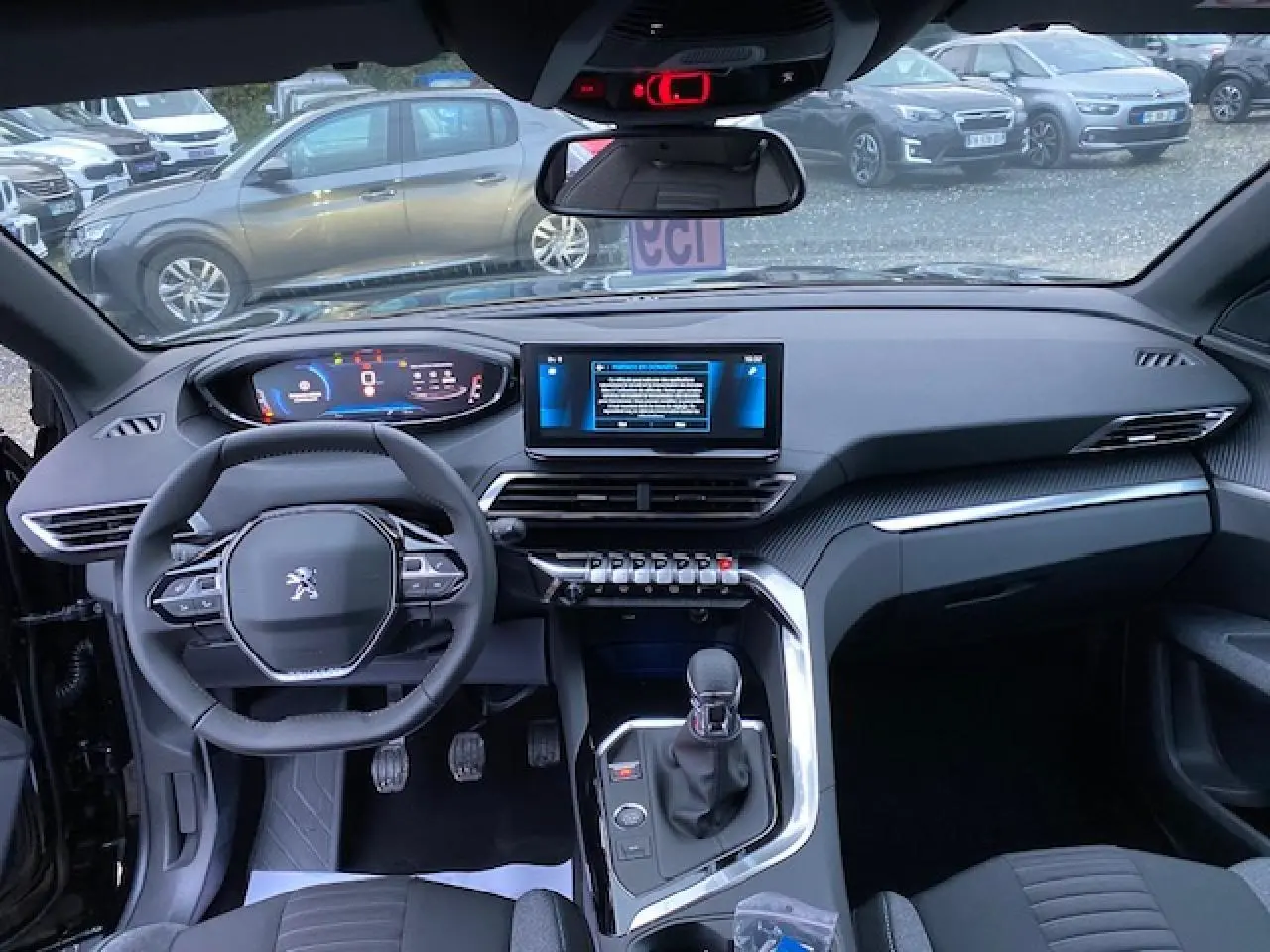 Vue intérieure avant du Peugeot 5008 noir 2023, tableau de bord moderne avec écran tactile et volant compact multifonction.