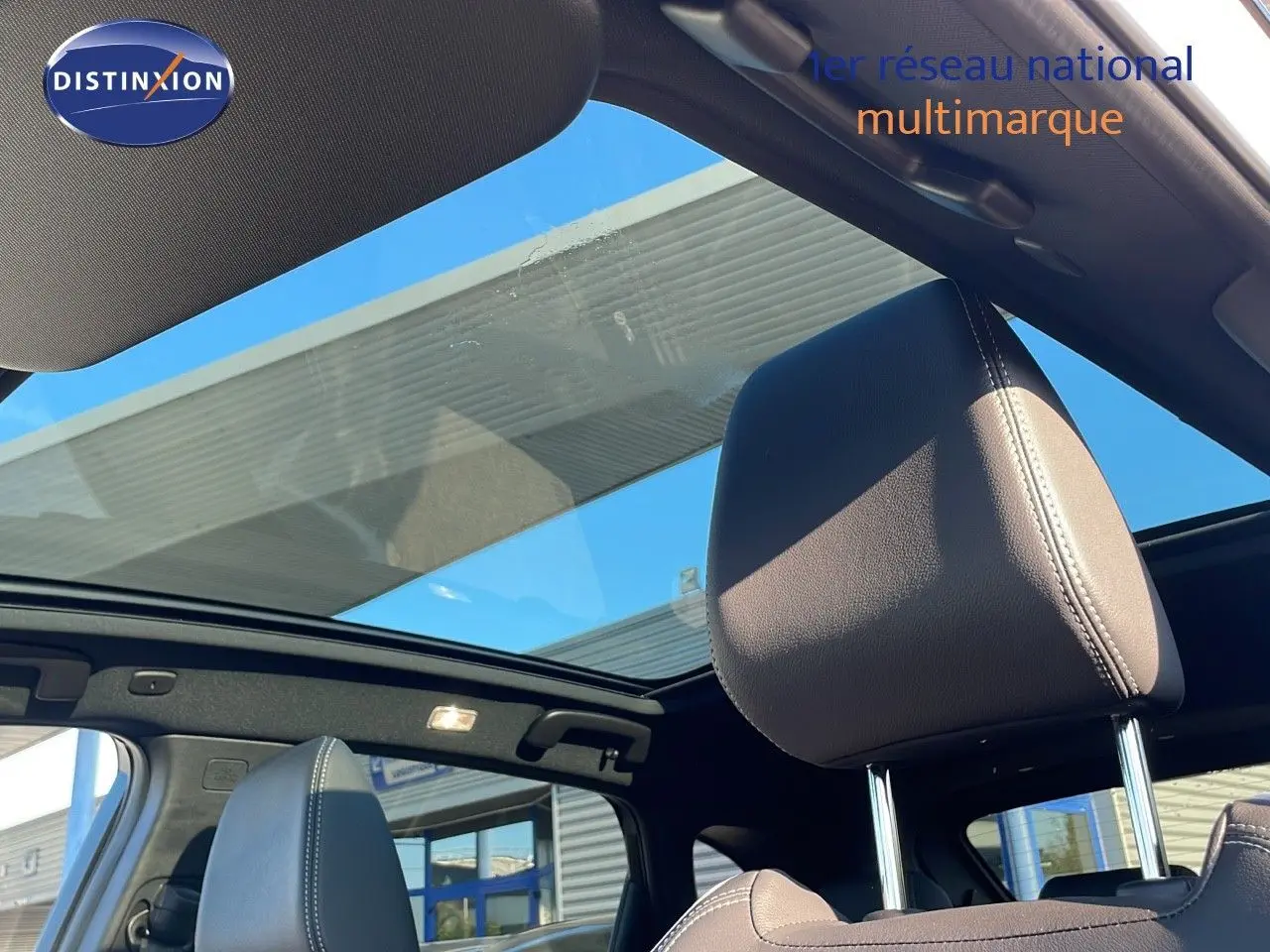 Vue intérieure sur les sièges avant en cuir noir et le toit panoramique du Nissan Qashqai blanc nacré 2025.