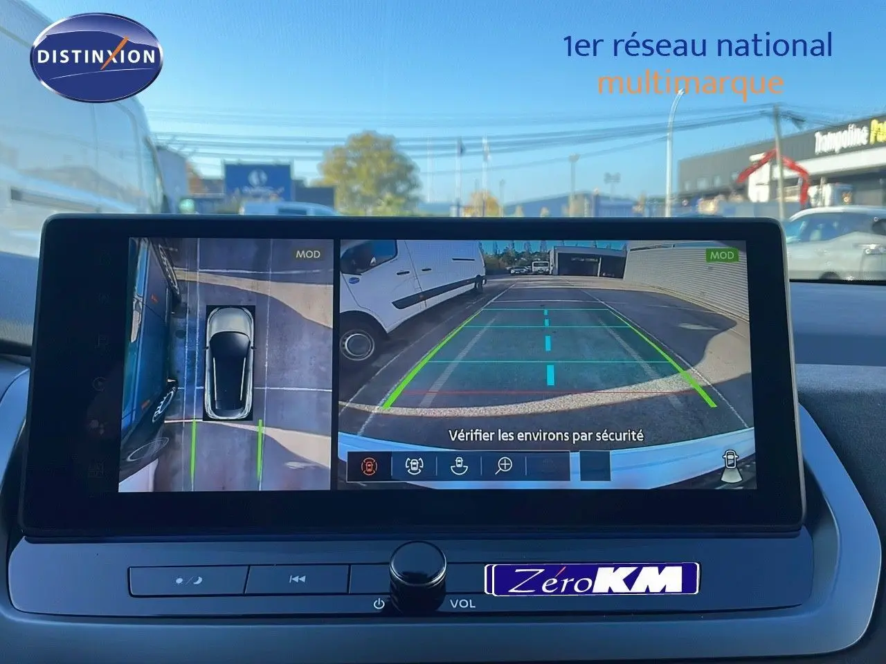 Écran multimédia du Nissan Qashqai blanc nacré, affichant la caméra de recul avec vue arrière et vue aérienne du parking.