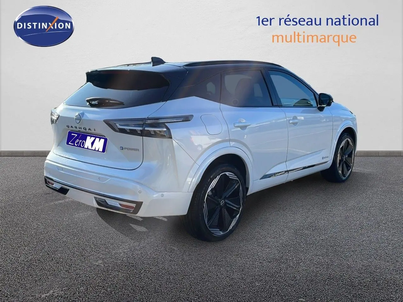 Vue 3/4 arrière droite du Nissan Qashqai blanc nacré avec toit noir et jantes noires brillantes.
