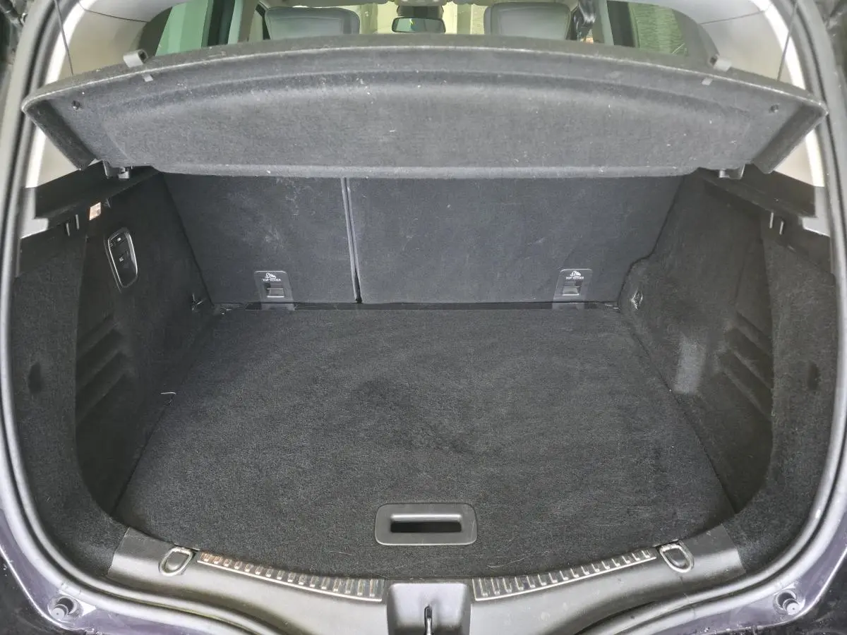 Coffre ouvert vu de l'arrière d'un Renault Scenic noir, montrant un espace de chargement propre et spacieux.