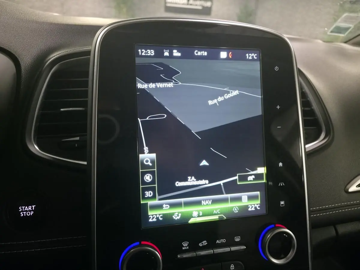 Écran tactile central du Renault Scenic 2018 affichant la navigation, entouré de commandes de climatisation et bouton Start/Stop.