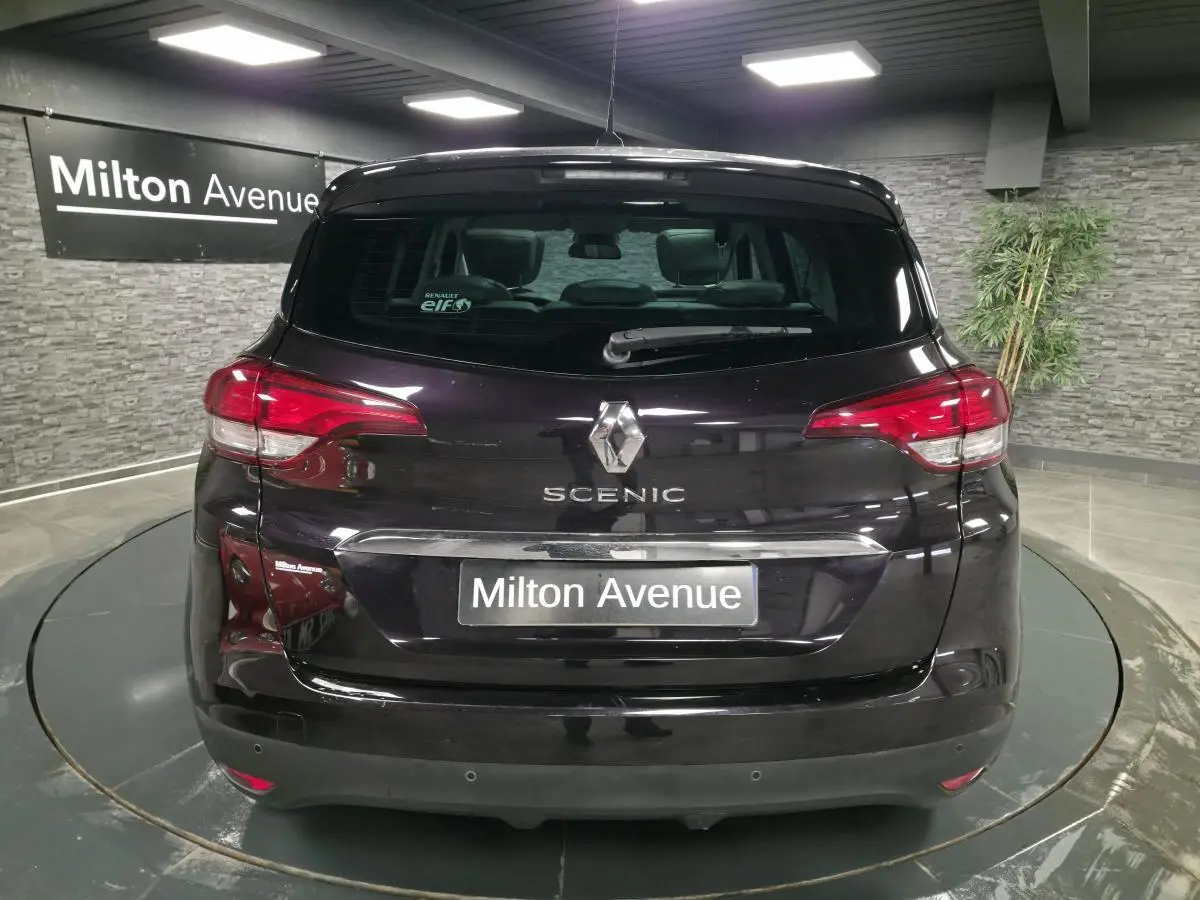 Vue arrière d'un Renault Scénic noir avec logo et nom du modèle visibles, dans un showroom intérieur.
